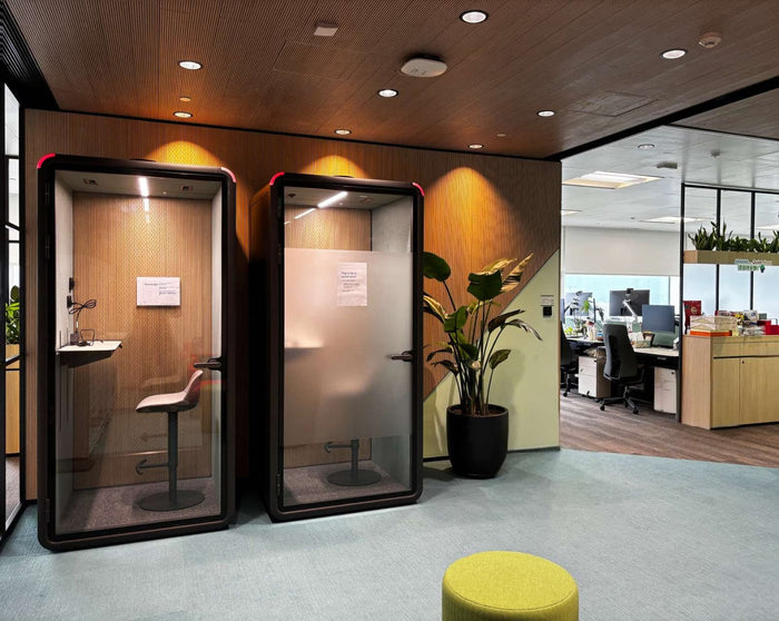 Open-plan office floor with an acoustic booth in use