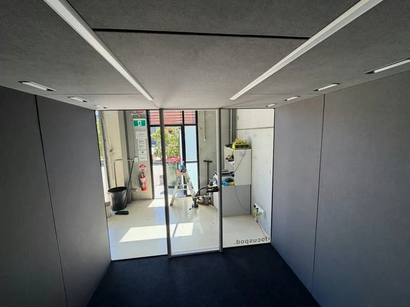 Unfurnished FocusPod Max interior with grey walls, dark flooring, ceiling lighting and a glass frontage.